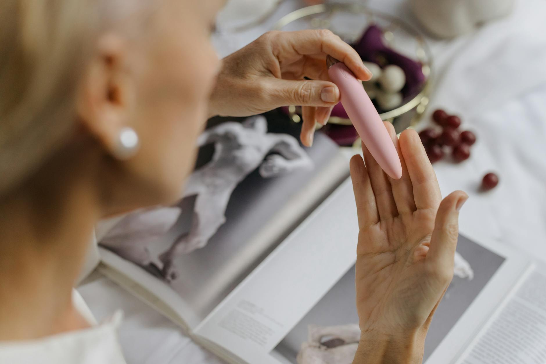 Donna che tiene in mano un vibratore al limone, sullo sfondo libri d'arte