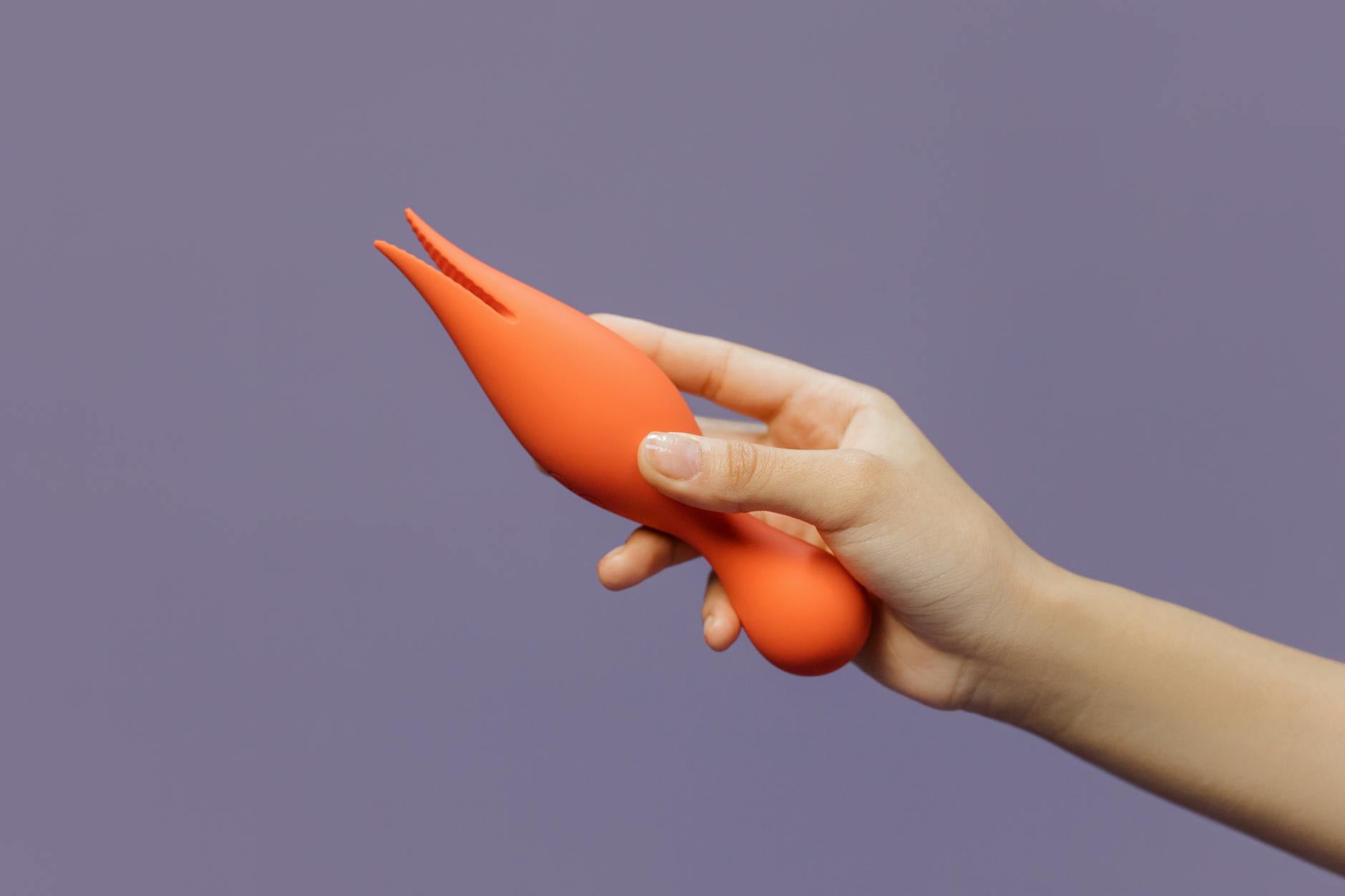 Woman holding blue and pink vibrators in contemplation