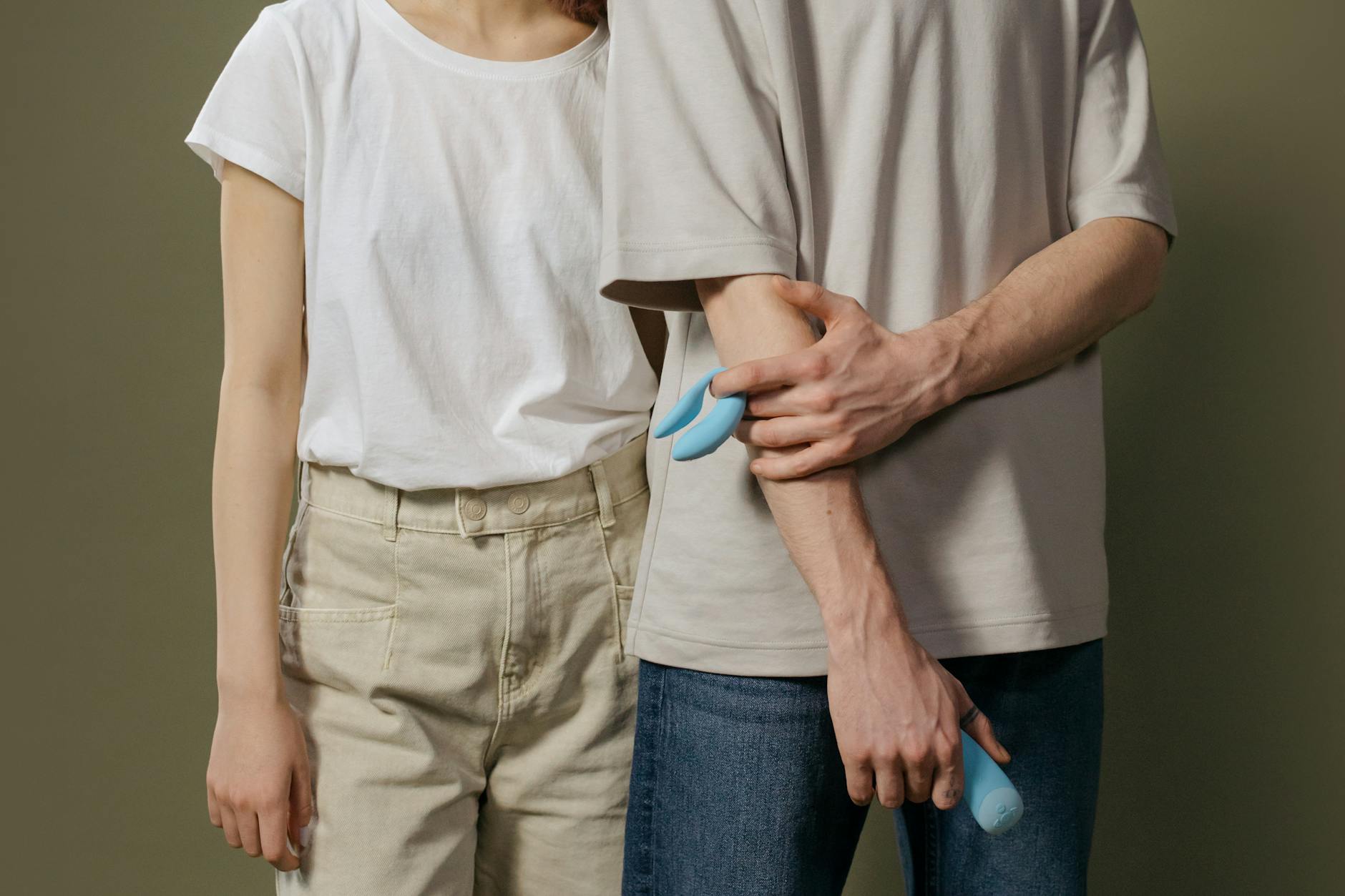 A close-up view of a hand holding a blue vibrator above a decorative glass bowl.